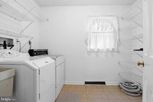 clothes washing area featuring laundry area, visible vents, washer and clothes dryer, and baseboards