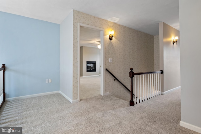 corridor featuring carpet floors, wallpapered walls, baseboards, and an upstairs landing