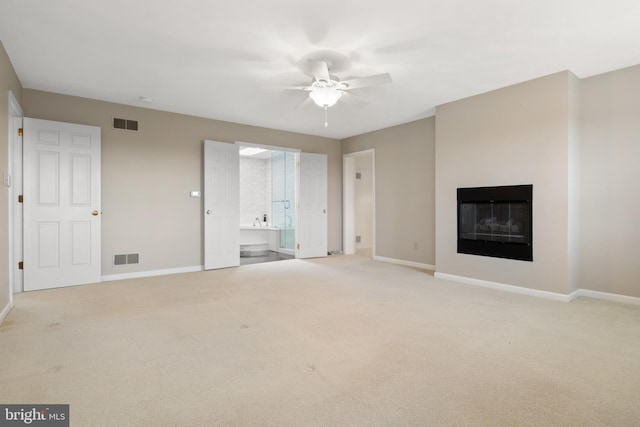 unfurnished living room featuring light carpet, a glass covered fireplace, visible vents, and baseboards