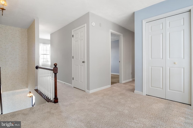 corridor featuring carpet floors, baseboards, and an upstairs landing