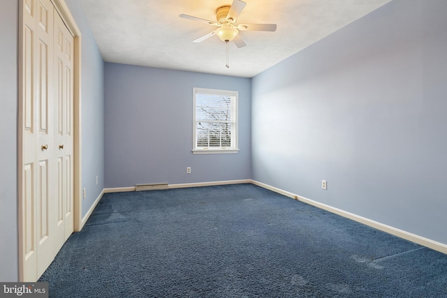 unfurnished bedroom featuring dark colored carpet, a closet, a ceiling fan, and baseboards