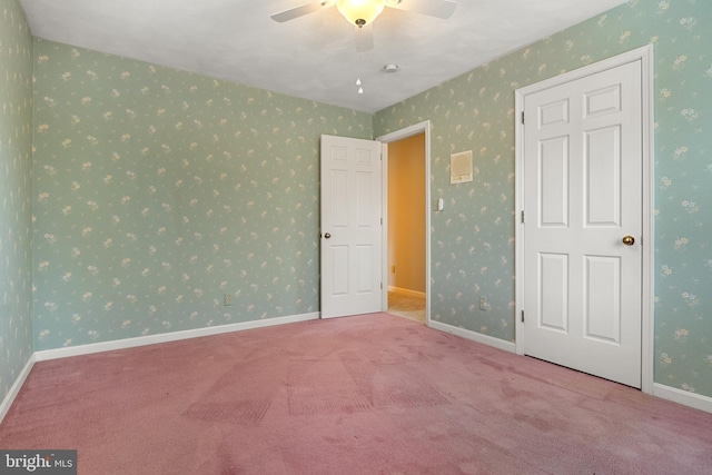 unfurnished room with carpet floors, wallpapered walls, baseboards, and a ceiling fan