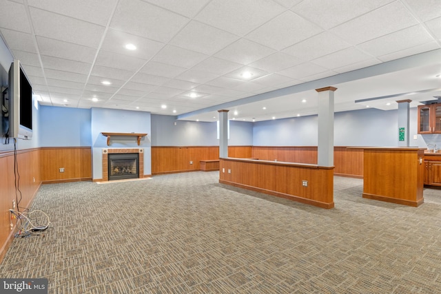 finished below grade area featuring recessed lighting, light carpet, wood walls, wainscoting, and a tiled fireplace