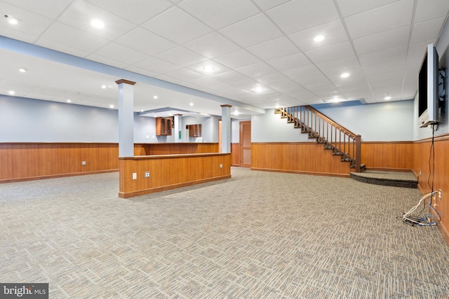 finished basement with a wainscoted wall, stairway, carpet flooring, and wooden walls