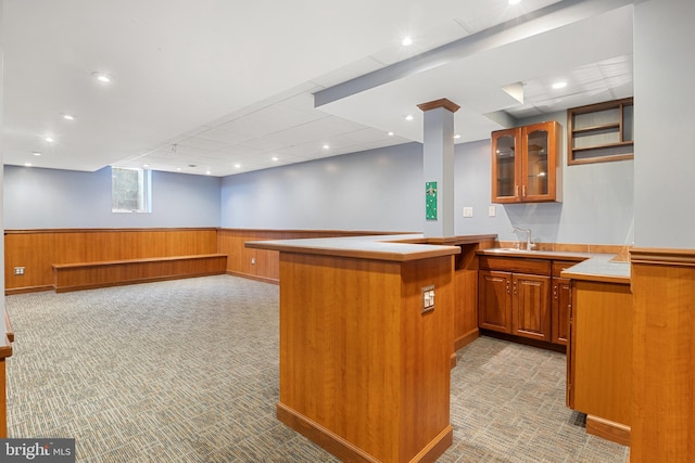 bar featuring wooden walls, light colored carpet, a sink, wainscoting, and wet bar