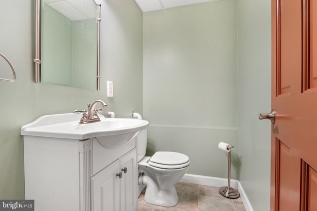 half bath with toilet, tile patterned flooring, vanity, and baseboards