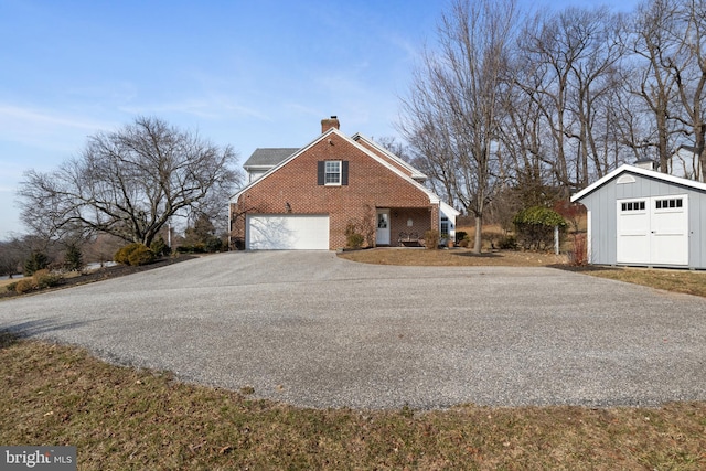 view of property exterior with brick siding, a chimney, a shed, driveway, and an outdoor structure