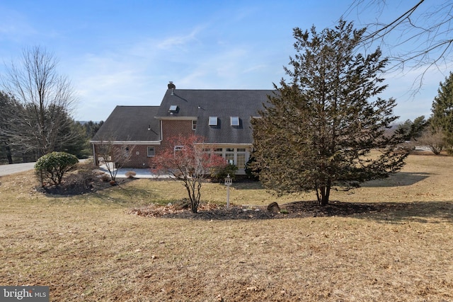 back of house featuring a chimney, a patio area, and a lawn