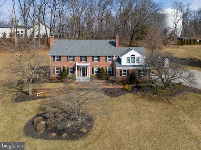 view of front of house featuring a front yard, brick siding, and a chimney