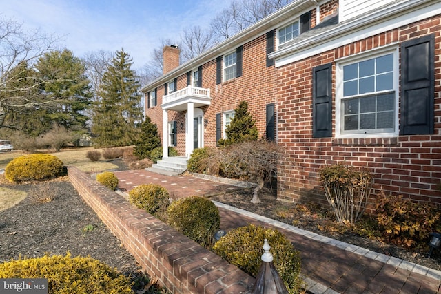 view of side of home featuring brick siding and a chimney