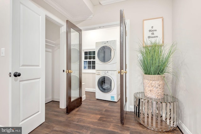 laundry area featuring stacked washer and dryer, laundry area, wood finished floors, baseboards, and ornamental molding