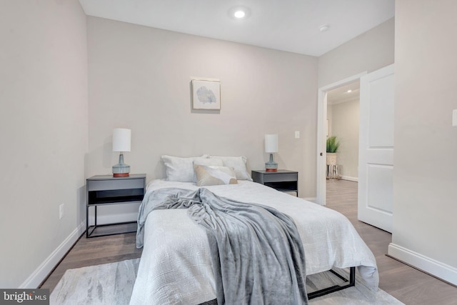 bedroom with recessed lighting, wood finished floors, and baseboards