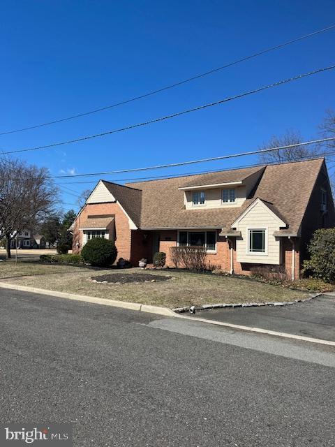 view of front of house with brick siding and roof with shingles