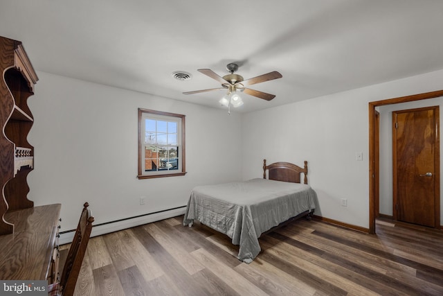 bedroom with wood finished floors, visible vents, baseboards, ceiling fan, and baseboard heating