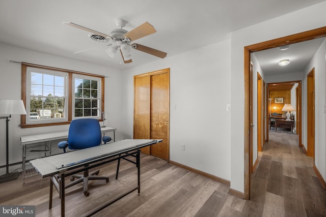 office area featuring ceiling fan, visible vents, baseboards, and wood finished floors