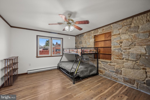 bedroom with wood finished floors, a baseboard heating unit, baseboards, and ornamental molding