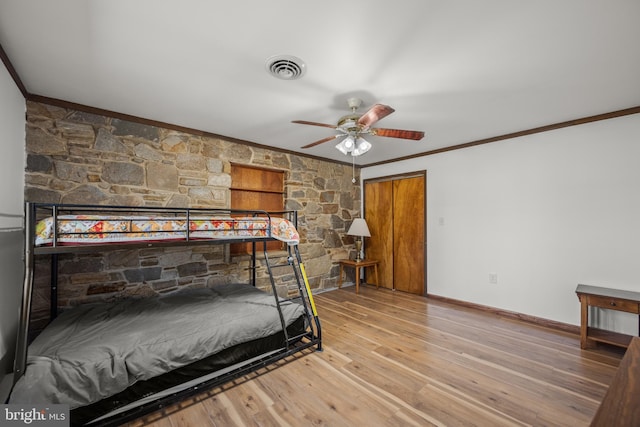 bedroom featuring visible vents, baseboards, wood finished floors, and crown molding