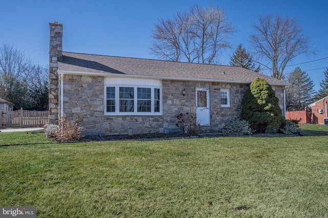 view of front of home featuring roof with shingles, a chimney, a front lawn, and fence