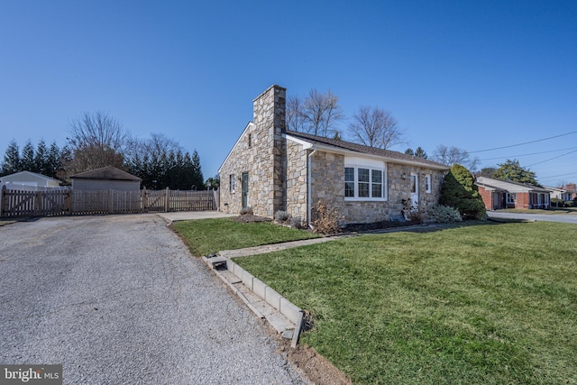 view of front of home featuring aphalt driveway, a chimney, a front yard, and fence