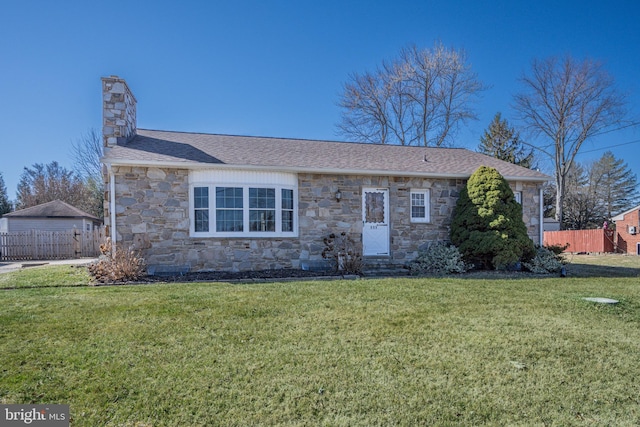 view of front of property with stone siding, a chimney, a front lawn, and fence