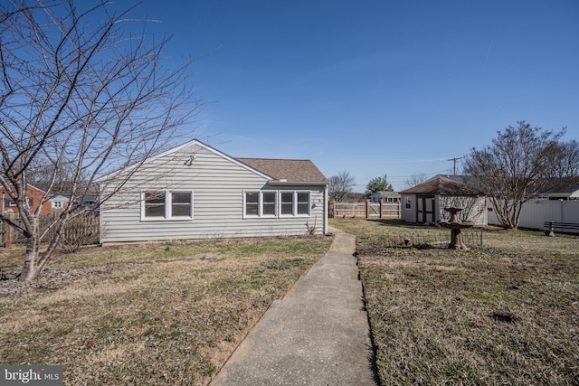 rear view of house featuring a yard, fence, and roof with shingles