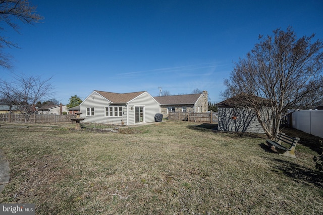 rear view of property featuring a lawn and a fenced backyard