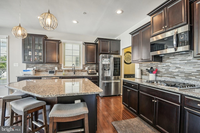 kitchen with light stone countertops, dark brown cabinetry, a kitchen bar, and stainless steel appliances