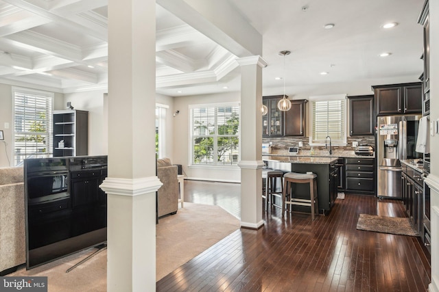 kitchen with a kitchen breakfast bar, open floor plan, decorative columns, and stainless steel fridge with ice dispenser