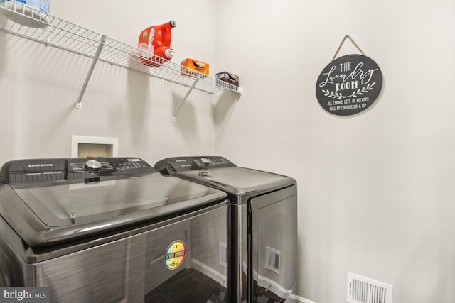 washroom featuring laundry area, visible vents, and separate washer and dryer