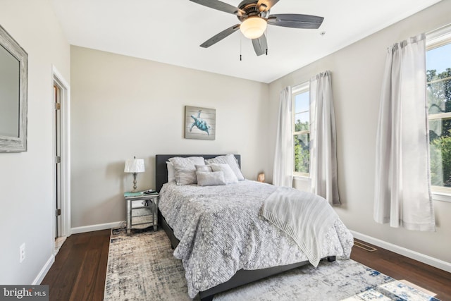 bedroom featuring multiple windows, wood finished floors, and baseboards