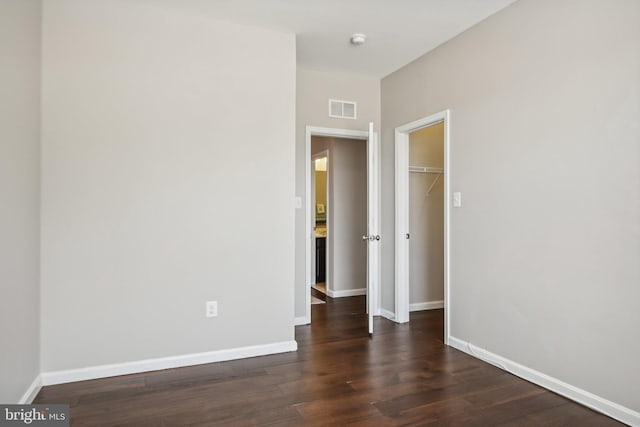 interior space with dark wood-style floors, visible vents, and baseboards