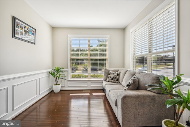 living area with a wainscoted wall, a decorative wall, and hardwood / wood-style floors