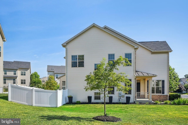 rear view of property with brick siding, a lawn, and fence