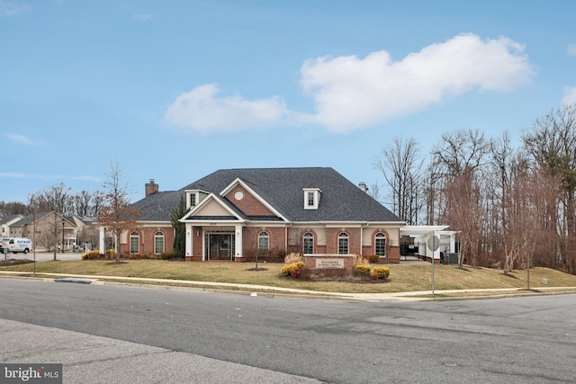 view of front of home featuring a shingled roof, a chimney, a front lawn, and brick siding