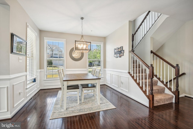 dining room featuring a chandelier, dark wood-style flooring, stairs, and a wainscoted wall