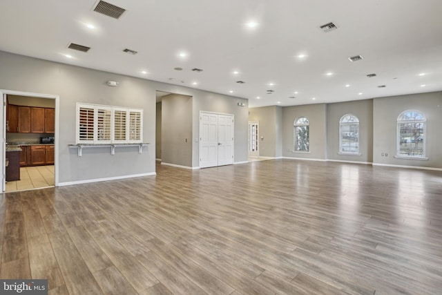 unfurnished living room with light wood-type flooring and visible vents