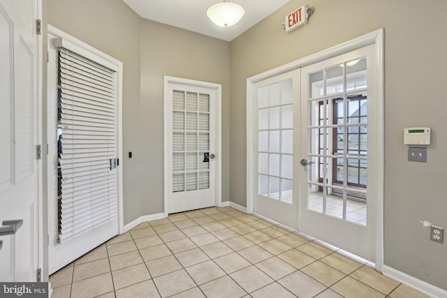 doorway with light tile patterned floors, baseboards, and french doors