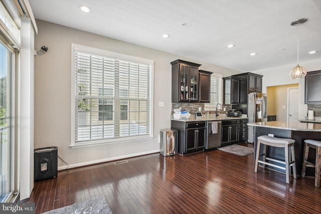 kitchen with glass insert cabinets, plenty of natural light, appliances with stainless steel finishes, and a sink