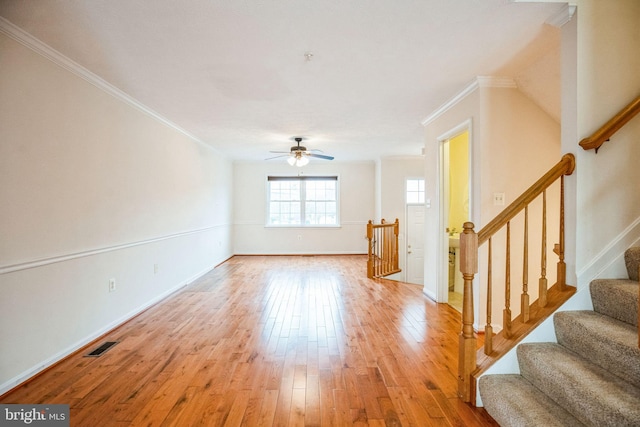 interior space with light wood-type flooring, visible vents, a ceiling fan, stairway, and crown molding