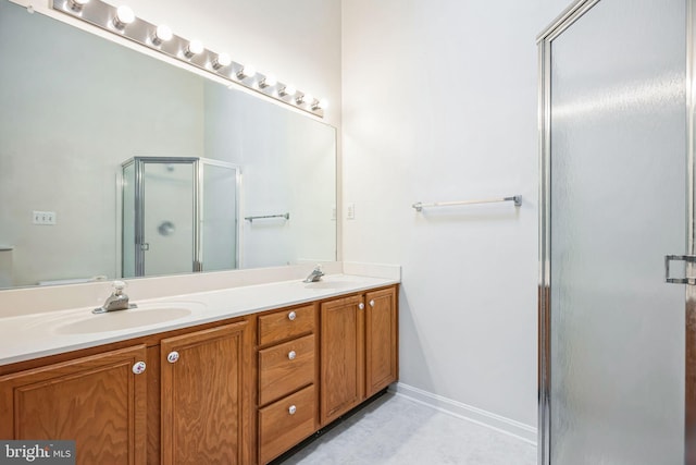 bathroom with a shower stall, double vanity, baseboards, and a sink