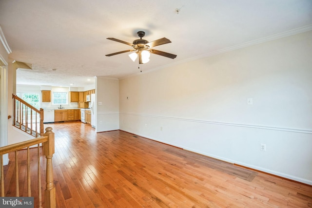 unfurnished living room with light wood-type flooring, baseboards, stairs, and crown molding