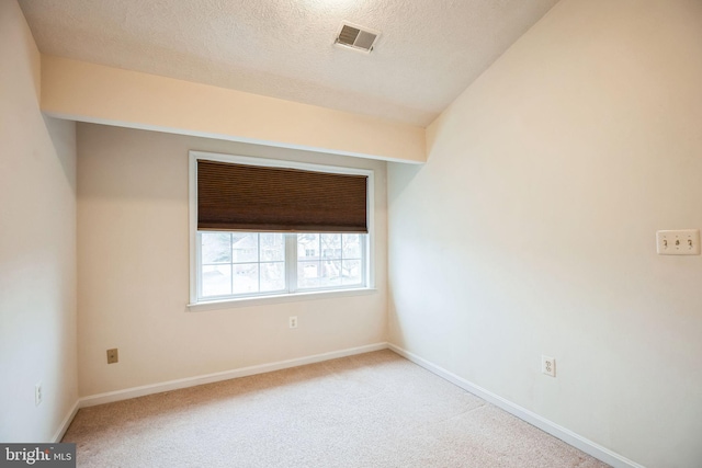 carpeted spare room featuring baseboards, visible vents, and a textured ceiling