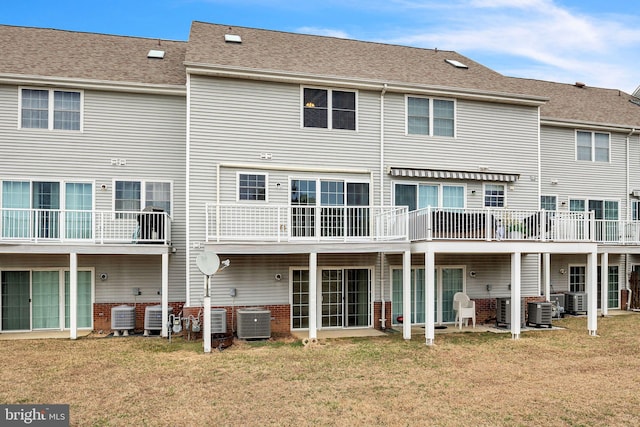 rear view of property featuring central air condition unit and a yard