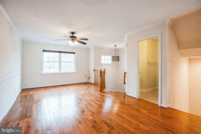 spare room with baseboards, wood-type flooring, ceiling fan, and crown molding