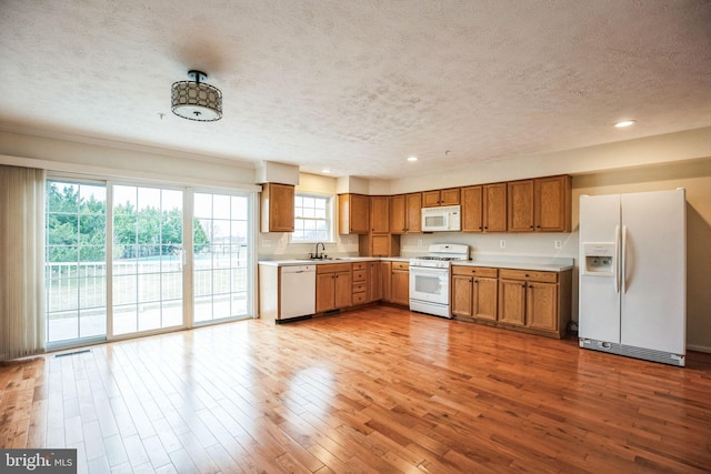 kitchen with white appliances, wood finished floors, light countertops, and a sink