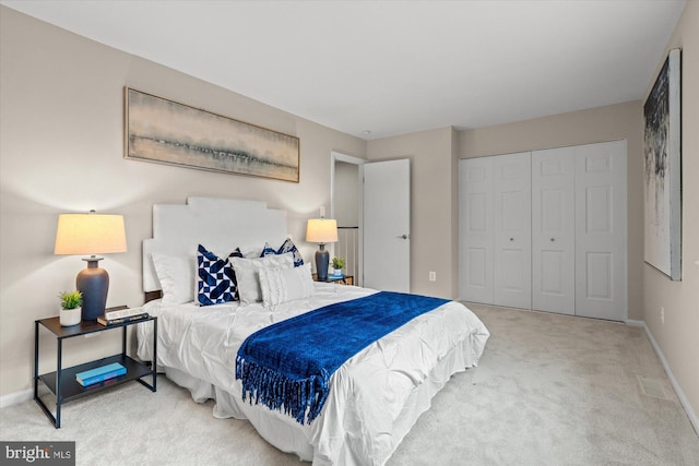 bedroom with a closet, light carpet, and baseboards