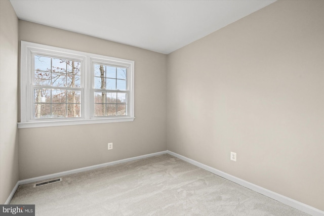 carpeted spare room featuring baseboards and visible vents