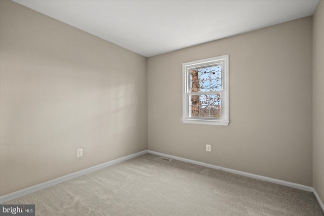 spare room with carpet, visible vents, and baseboards