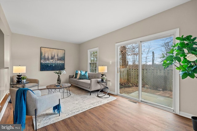 living room featuring baseboards, visible vents, and wood finished floors