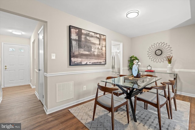 dining space featuring wood finished floors, visible vents, and baseboards